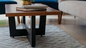 Un salon moderne avec une table basse en bois, deux canapés bleus, une lampe sur pied et une grande fenêtre.