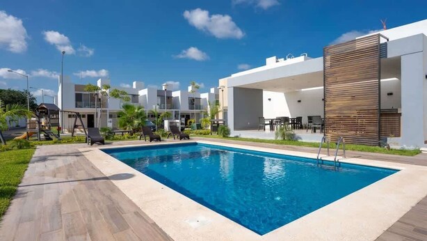 Un espace piscine moderne doté d’une piscine rectangulaire, de chaises longues et d’un paravent en bois assurant l’intimité.