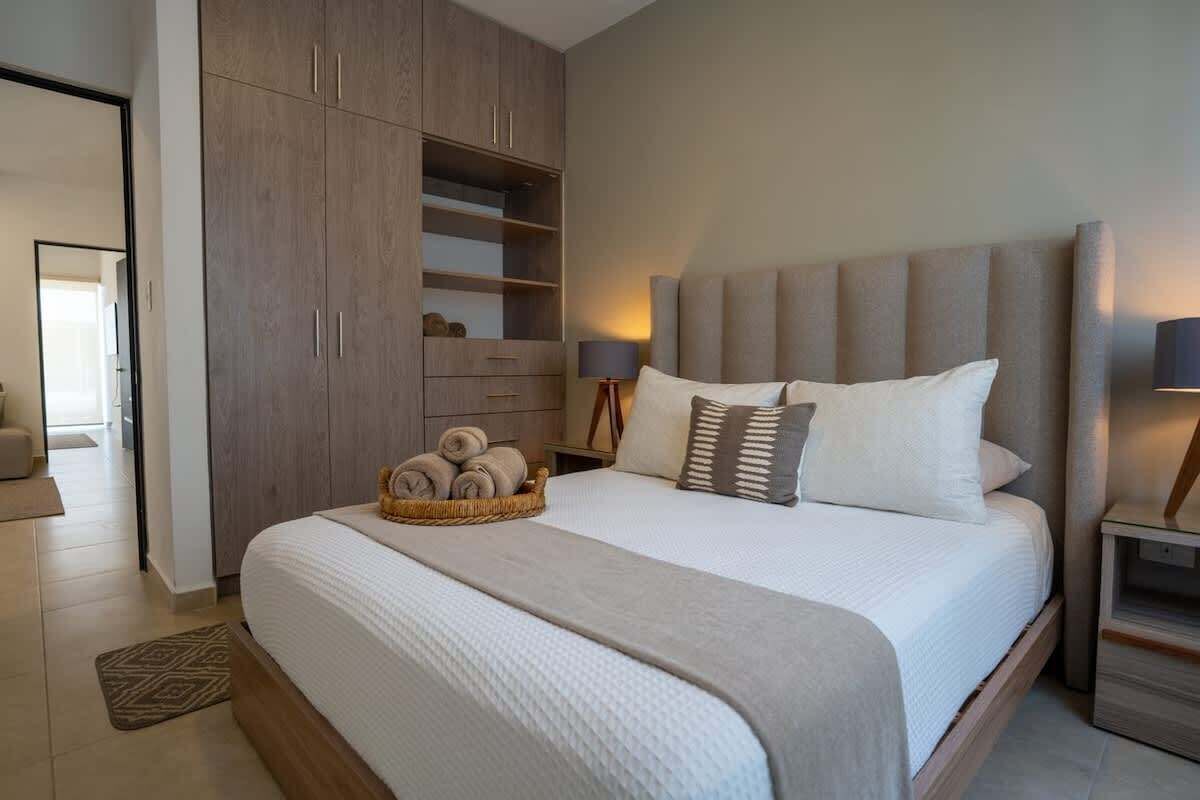 A modern bedroom with a large bed, a wardrobe, and a bedside table.