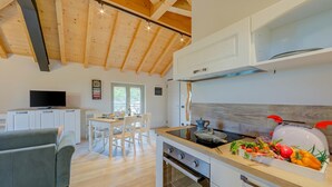 Eine moderne Küche mit Holzbalken, einem Essbereich mit Tisch und Stühlen sowie einem eingebauten Backofen.