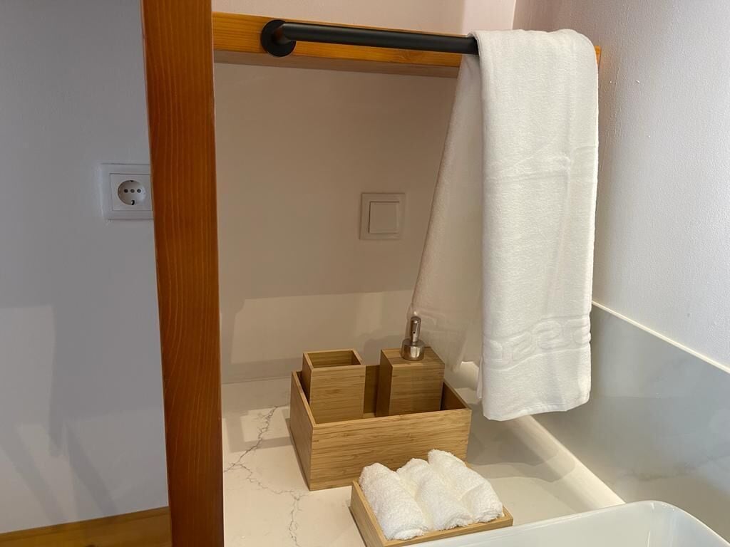 Ett badrum med ett trähandduksställ, en handduk som hänger på det och en trälåda med en handduk inuti.