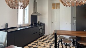 Une cuisine moderne avec des meubles de couleur sombre, un îlot central et un carrelage à motifs géométriques.