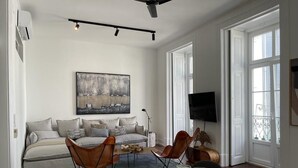 Un salon spacieux comprenant un canapé, des fauteuils, une table basse et un téléviseur.