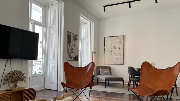 Un salon moderne doté d’un téléviseur à écran plat, de fauteuils en cuir, d’une table basse ronde et d’un grand tableau abstrait accroché au mur.