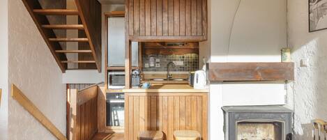 Une cuisine avec des meubles de rangement en bois, une cuisinière encastrée et un escalier en bois.
