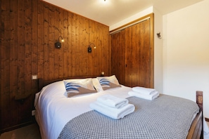 Een kamer met houten lambrisering, een bed, twee wandlampen en een deur.