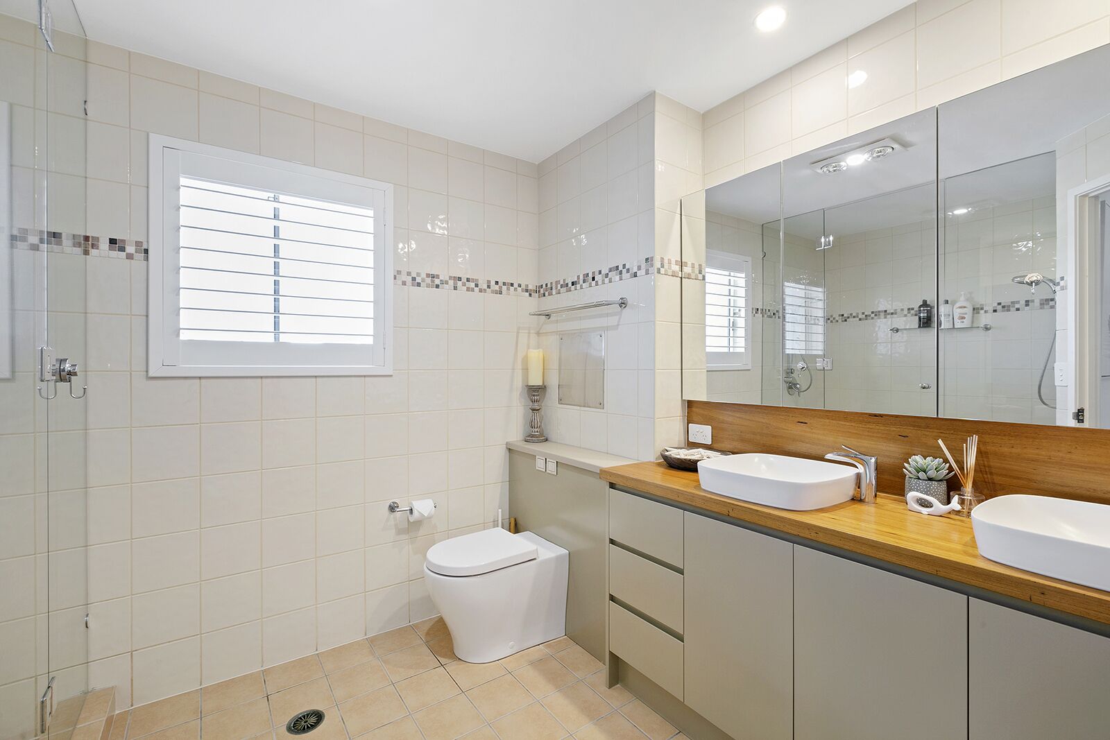 A modern bathroom with two sinks, a toilet, and a shower.