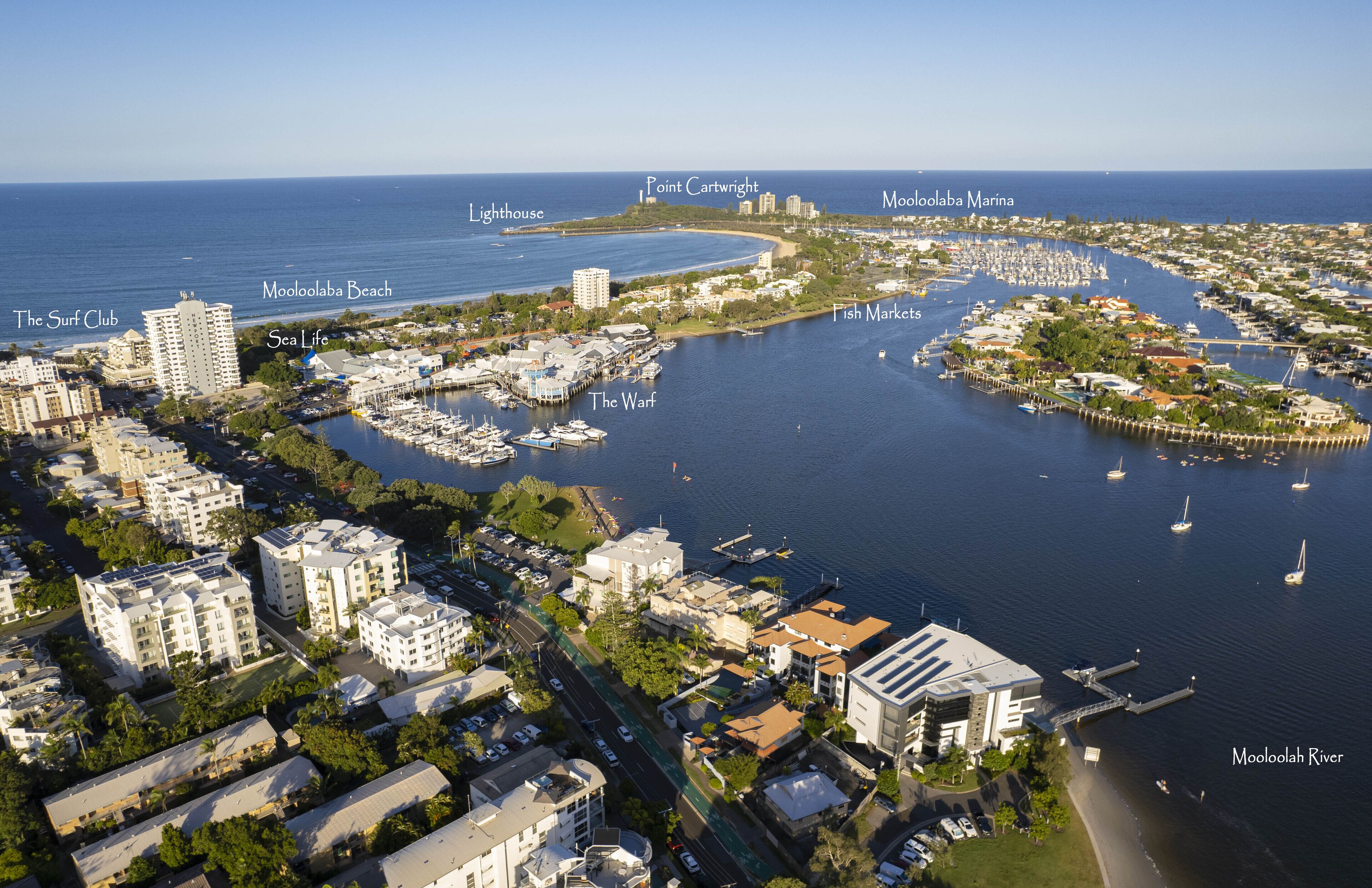 An aerial view of a coastal town with buildings, a marina, and a beach.