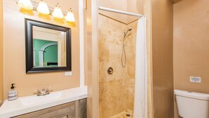 Un baño con lavamanos, espejo, ducha e inodoro.
