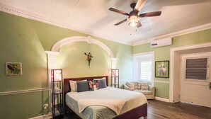 Un dormitorio con cama, ventilador de techo, ventana y puerta.