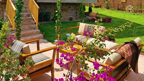A two-story house with a wooden balcony, a stone staircase, and a well-maintained garden with outdoor furniture. - Kallpawasi, Andean House in the Sacred Valley of the Incas. Service and Nature. (Urubamba)
