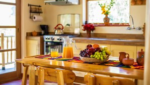 A wooden dining table with a fruit bowl, a pitcher of orange juice, and a glass of orange juice. - Kallpawasi, Andean House in the Sacred Valley of the Incas. Service and Nature. (Urubamba)