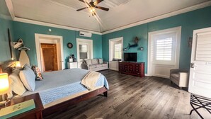 A bedroom with a bed, a dresser, a television, and a ceiling fan. - VERY Spacious 3rd floor unit with gorgeous ocean view and wrap around porch (Frederiksted)