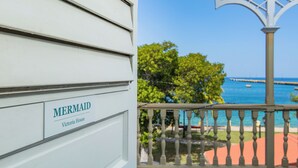 A white building with a sign reading "MERMAID Victoria House" and a balcony with a view of the sea and a pier. - VERY Spacious 3rd floor unit with gorgeous ocean view and wrap around porch (Frederiksted)
