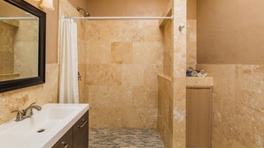 A bathroom with a shower, a sink, and a mirror. - VERY Spacious 3rd floor unit with gorgeous ocean view and wrap around porch (Frederiksted)