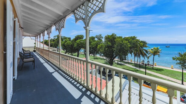 A balcony with a view of the ocean, featuring a railing and a few chairs. - 3rd floor unit with Picturesque Ocean View and outdoor seating! (Frederiksted)