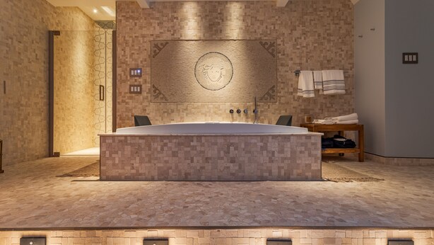 A modern bathroom with a large bathtub, a wall-mounted towel rack, and a textured wall design.