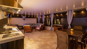 A spacious patio area with a dining table, chairs, and a grill station.
