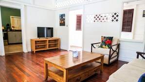 Een woonkamer met een houten salontafel, een tv-meubel, een bank en een fauteuil.
