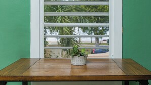 Een houten tafel met een potplant voor een raam met horizontale jaloezieën.