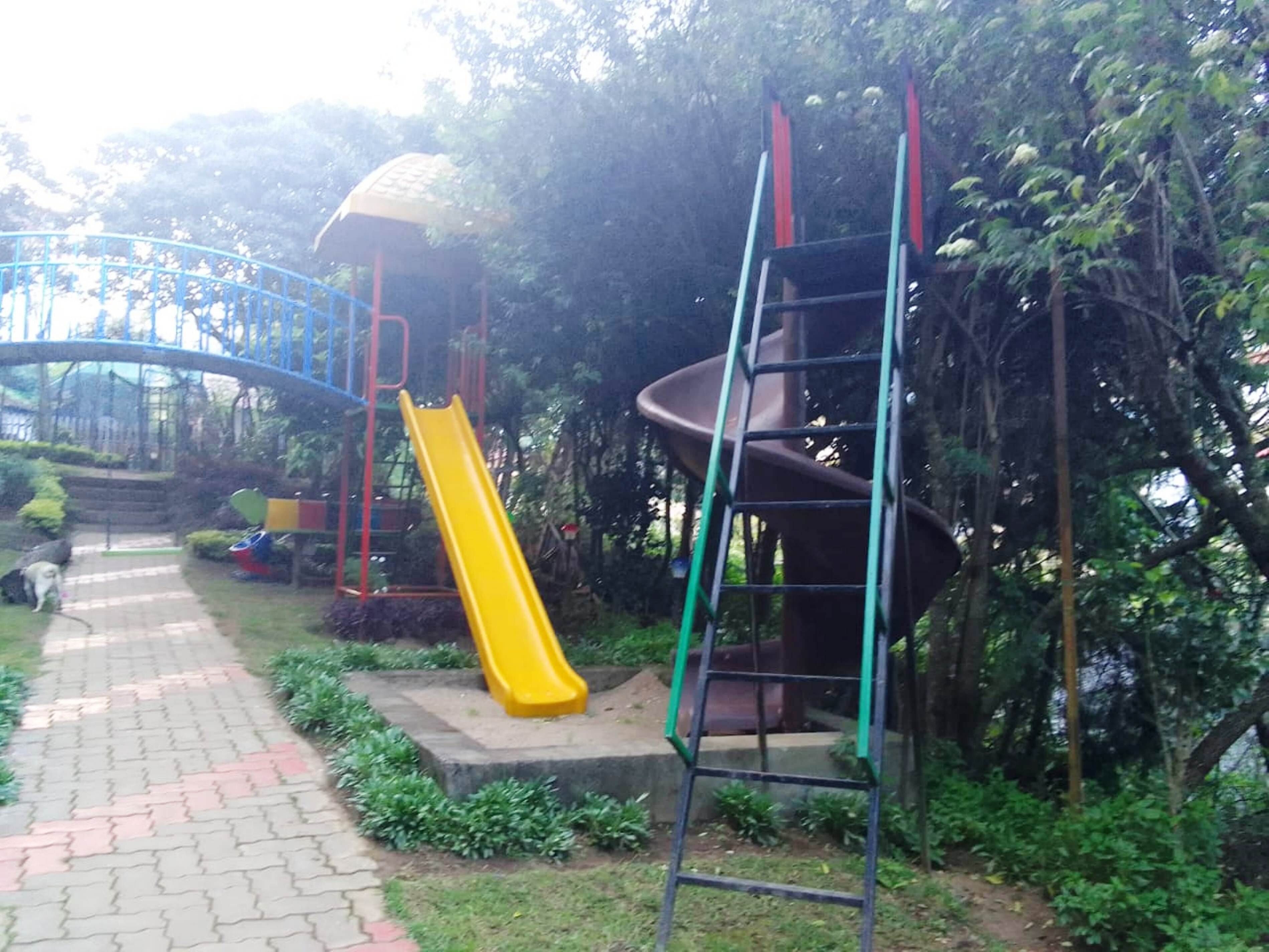 Une aire de jeux avec un toboggan jaune et une structure d’escalade.
