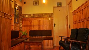 A wooden-paneled room with a bench, a table, and two chairs. - Pine Borough Inn (Kodaikanal)