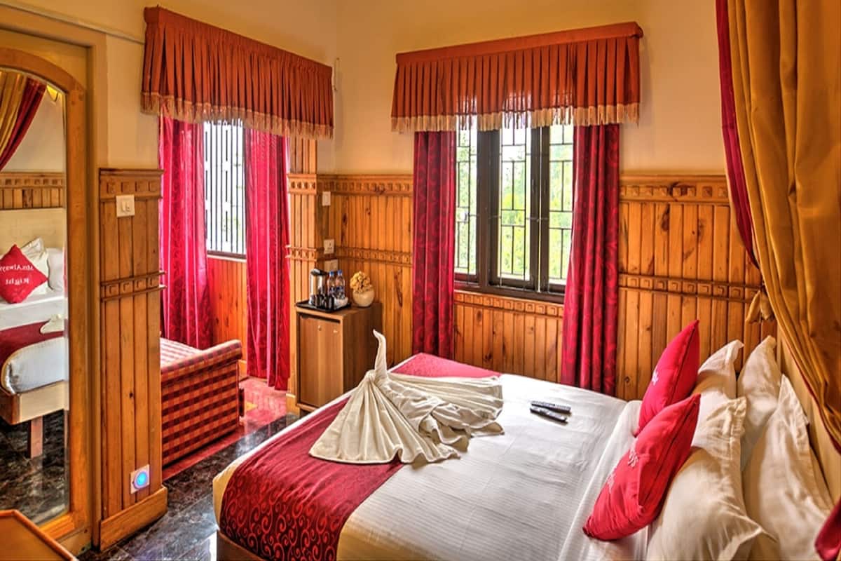 A hotel room with a bed, a wooden headboard, a nightstand, and a window with curtains.