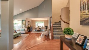A spacious living area with hardwood flooring, a dining table, and a staircase. - Luxe Scottsdale Home W/pool, Spa, & Tesla Charger (Scottsdale)