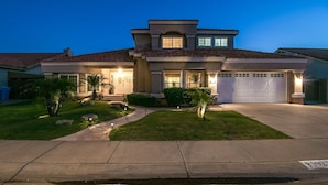 A two-story house with a garage, a well-maintained lawn, and a driveway. - Luxe Scottsdale Home W/pool, Spa, & Tesla Charger (Scottsdale)