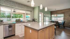 A modern kitchen with a large island, built-in appliances, and a dining area with a view. - Luxe Scottsdale Home W/pool, Spa, & Tesla Charger (Scottsdale)