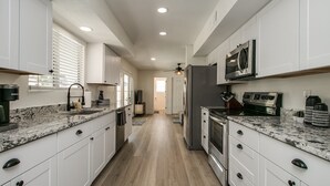 A modern kitchen with white cabinetry, granite countertops, stainless steel appliances, and a wooden floor. - Upgraded 4-bdrm Beautiful Home W/pool! (Glendale)