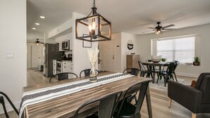 A modern kitchen with stainless steel appliances, a dining area with a wooden table and chairs, and a ceiling fan. - Upgraded 4-bdrm Beautiful Home W/pool! (Glendale)
