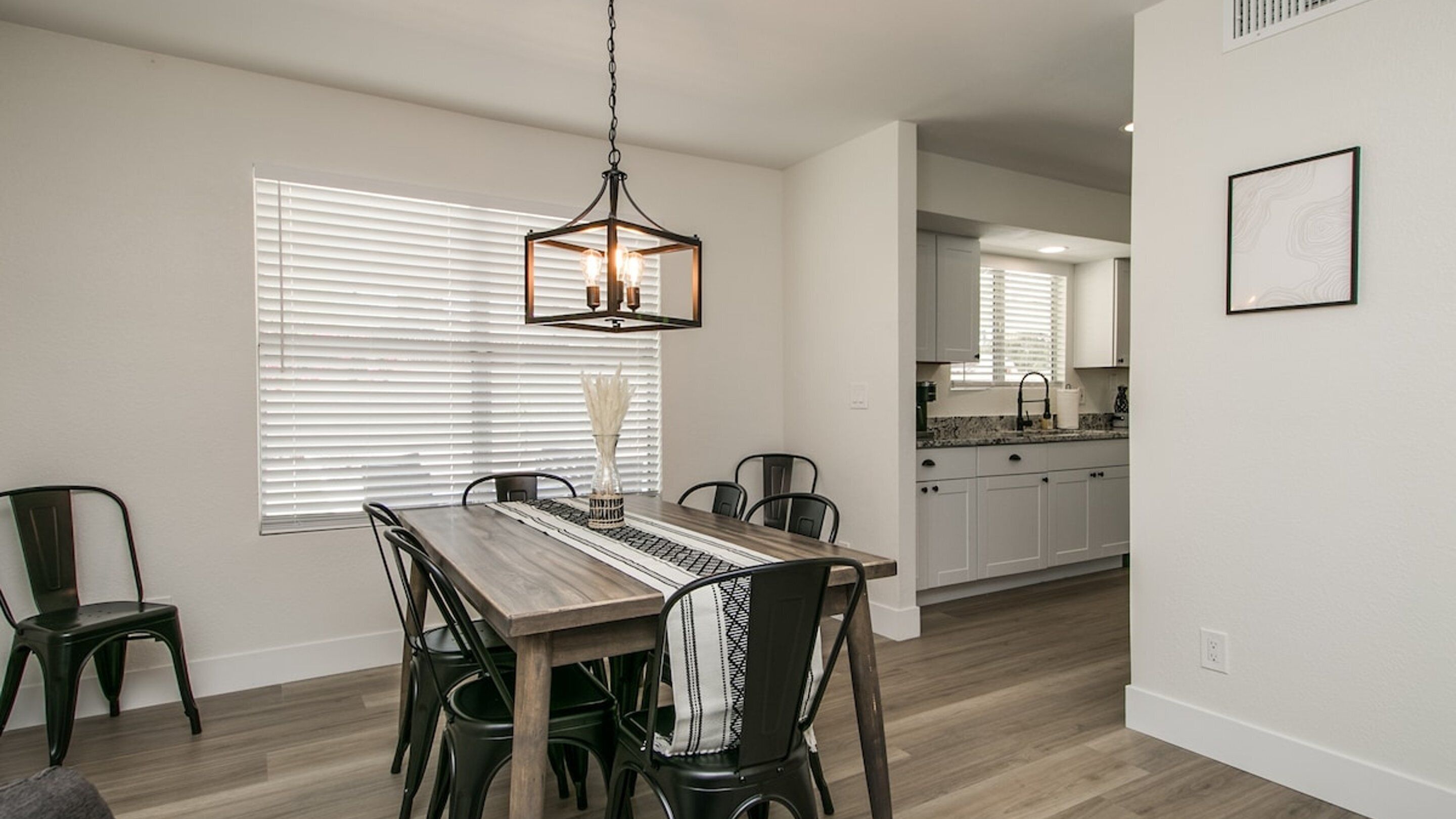 A dining area with a wooden table, chairs, and a hanging light fixture.
