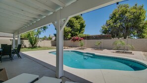 A covered outdoor area with a swimming pool, patio furniture, and a small garden with flowering plants. - Upgraded 4-bdrm Beautiful Home W/pool! (Glendale)