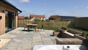 Un jardin avec un jacuzzi, des meubles de patio et une clôture en bois.