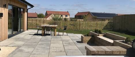 A backyard with a hot tub, patio furniture, and a wooden fence.