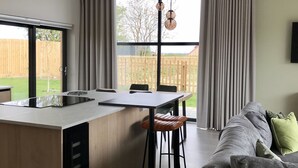 Une cuisine moderne dotée d’un îlot central, un coin repas avec une table et des chaises, et un espace de vie avec un canapé.