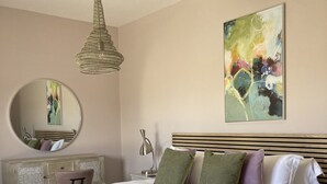 A bedroom with a bed, a round mirror, a painting, and a hanging light fixture. - Water Lily Cottage, Ashlin Farm Barns (Lincoln)