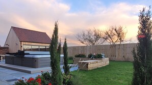 A backyard with a hot tub, wooden deck, and a fenced area with a wooden fence and trees. - Chestnut House, Ashlin Farm Barns (Lincoln)