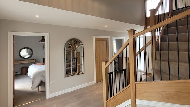 A spacious interior with a wooden staircase, a large chandelier, and a view into a bedroom. - Chestnut House, Ashlin Farm Barns (Lincoln)