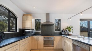 Una cocina moderna con armarios de madera, un horno de acero inoxidable, un microondas y un ventanal grande.