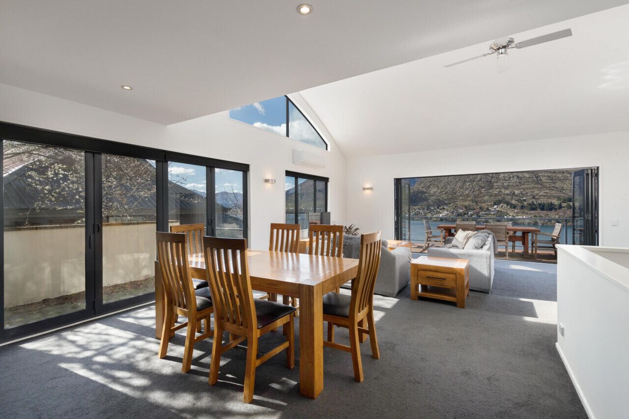 A modern interior with a dining area, seating, and large windows offering a view of the outdoors.