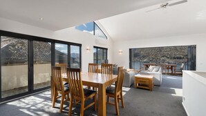 Un interior moderno con zona de comedor, asientos y ventanas amplias que ofrecen vistas al exterior.