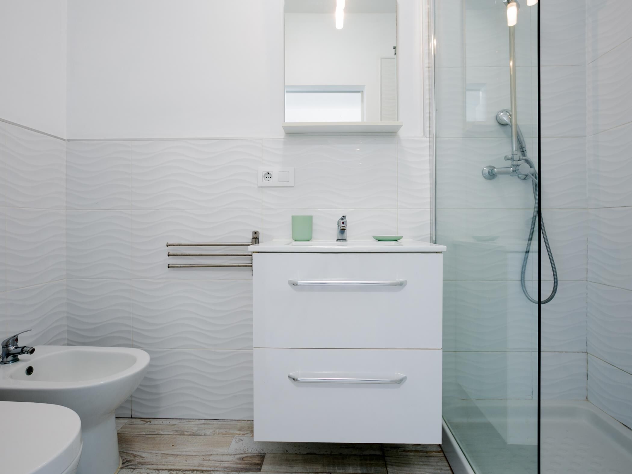 A modern bathroom with a bidet, a sink, and a glass shower enclosure.