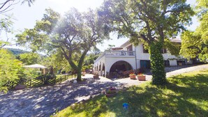 A building with a covered entrance, surrounded by trees and potted plants. - Apartment in Residence by the sea set in an amazing Park (Campiglia Marittima)