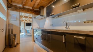Een moderne keuken met donkere kastjes, roestvrijstalen apparatuur en een houten plafond.