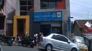A building with a blue sign for Canara Bank ATM, a sign for Joydeep Theaters, and a sign for a dry cleaning service. - Jayaraj Residency (Kodaikanal)