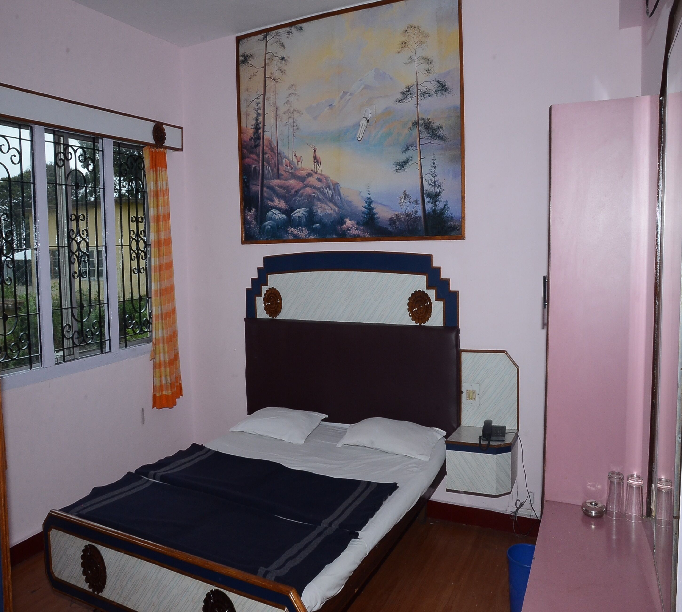 A bedroom with a bed, a nightstand, a painting, a window with curtains, and a door.