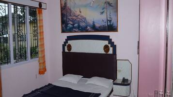 A bedroom with a bed, a nightstand, a painting, a window with curtains, and a door.