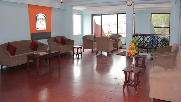 A spacious living room with multiple sofas and armchairs, a wooden coffee table, and a decorative vase with flowers. - Jayaraj Residency (Kodaikanal)